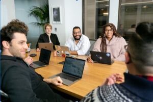 Team members collaborating in an office conference room, seated around a table, actively discussing key features of request for proposal (RFP) software designed to enhance operational efficiency
